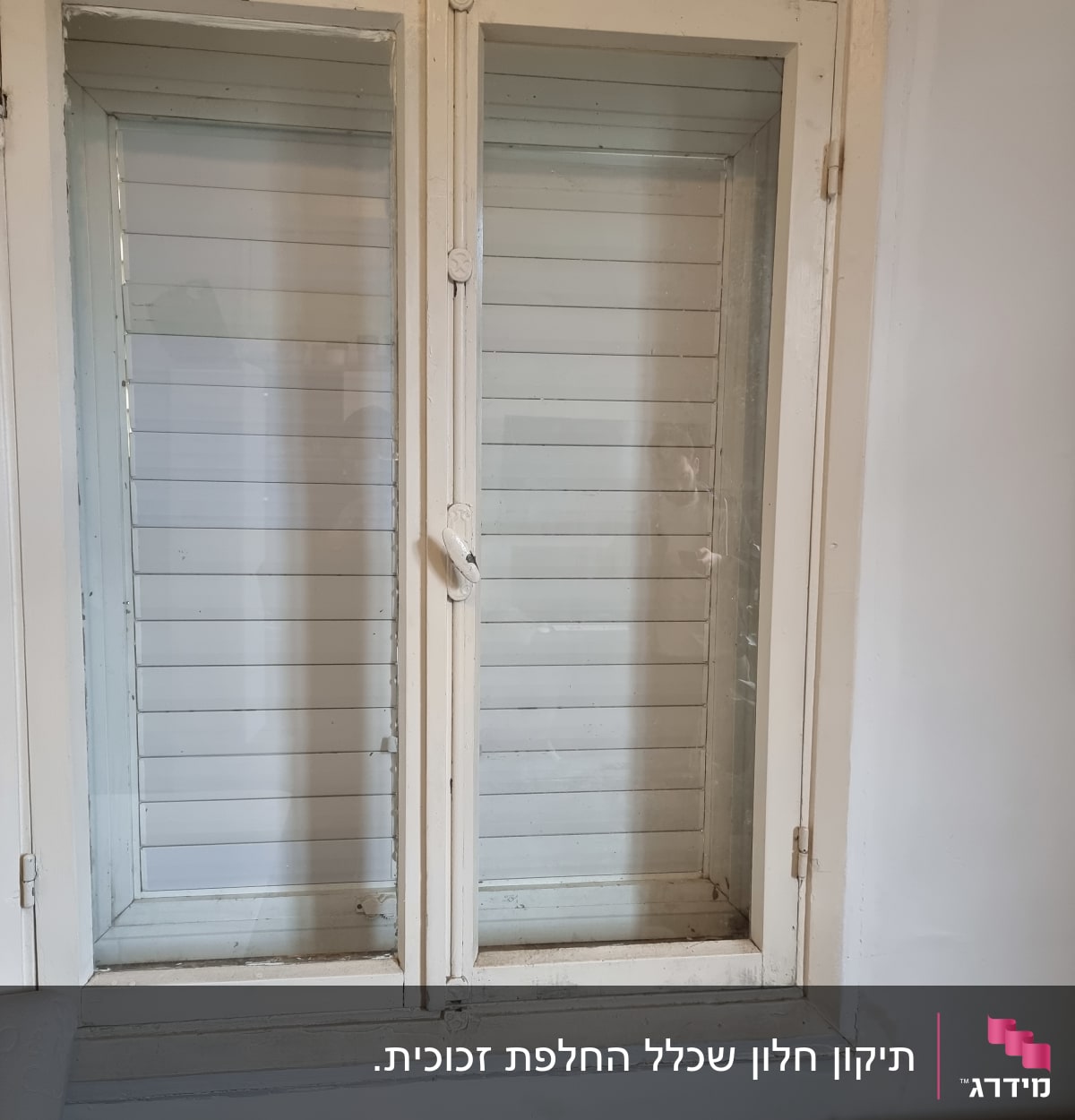 חלון זכוכית עם תריסים סגורים במסגרת עץ לבנה